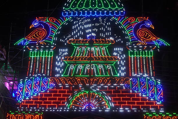 Colorful LED temple facade with peacock light motifs at night street festival