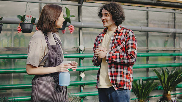 istock Two people engage in conversation while working together in a greenhouse full of plants on a sunny afternoon 2244138844