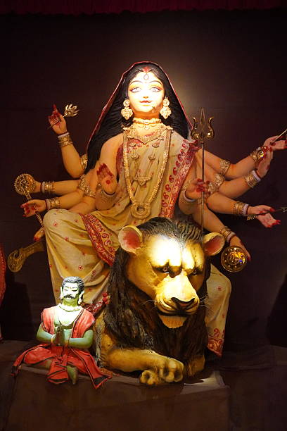 Front view of illuminated Goddess Durga idol seated on lion in dark background