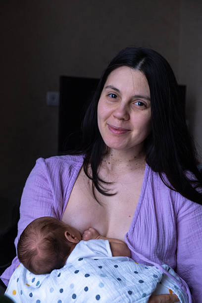 istock Mother Breastfeeding Baby by Window 2244141723