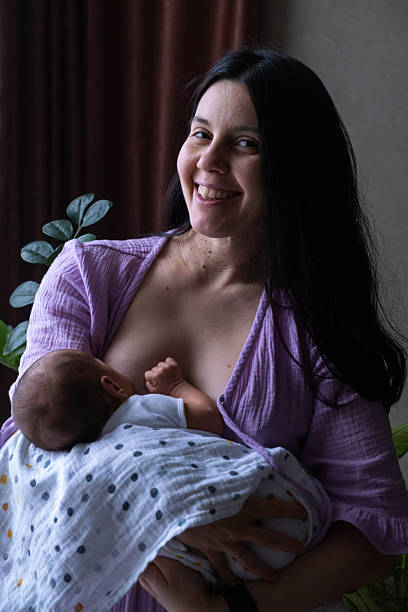 istock Mother Breastfeeding Baby by Window 2244141727