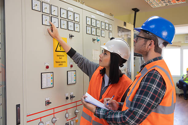 istock Young Female and Male Engineers Operating Electrical Control Panel in Modern Power Plant Control Room with Safety Helmets and High Visibility Vests 2244142001