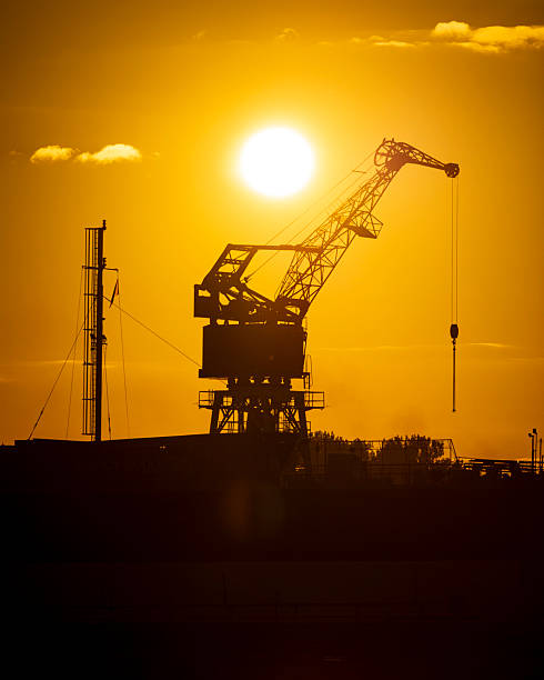 istock Beautiful metal crane silhouettes against the setting sun disc in harbour. 2244143794