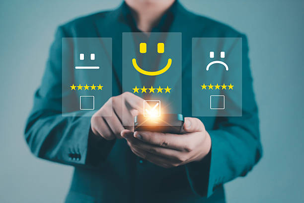 istock Businessman using smartphone to select digital satisfaction rating with smiley face icons, representing customer feedback, online review, service evaluation, user experience, and business quality 2244143814
