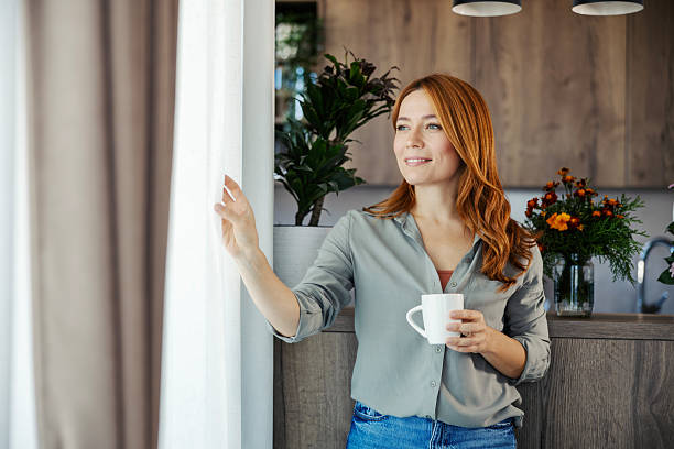 istock Woman drinking coffee at home looking out window 2244145931