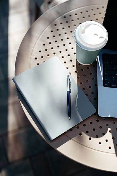 istock Workspace setup with notebook, pen, coffee cup, and laptop in outdoor setting 2244149635