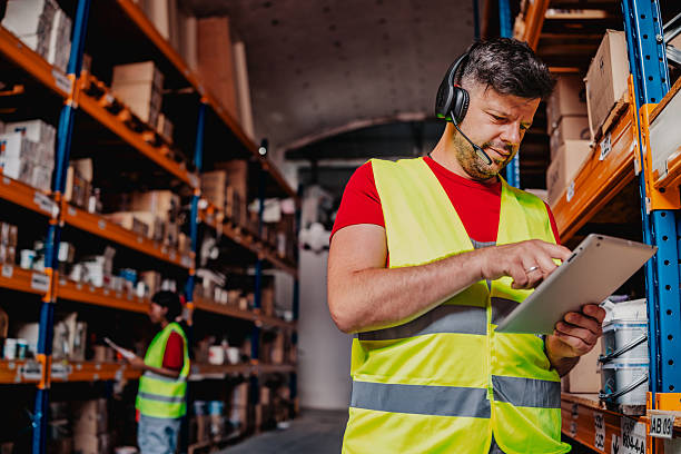 istock Warehouse workers collaborating in a distribution center while reviewing inventory on a tablet and managing supplies safely 2244149832