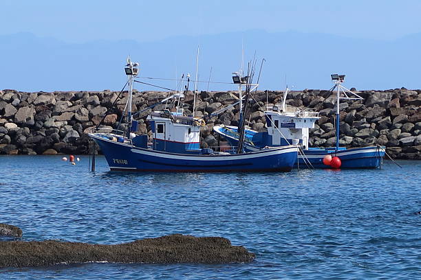 San Miguel de Tajao, Tenerife, Spain, October 26, 2025: Fishing boats at the breakwater of the fishing port of Tajao, Tenerife, Spain