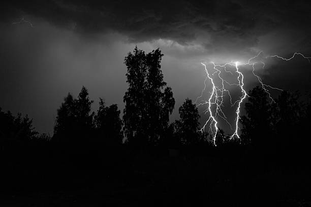 beautiful lightning during a thunderstorm at night in a forest that caused a fire, against a dark sky with rain