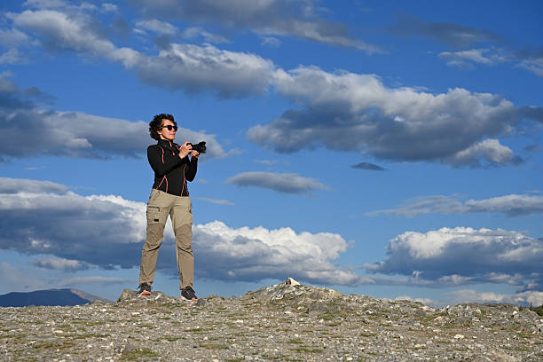 Middle-aged female tourist with a camera hiking in the mountains
