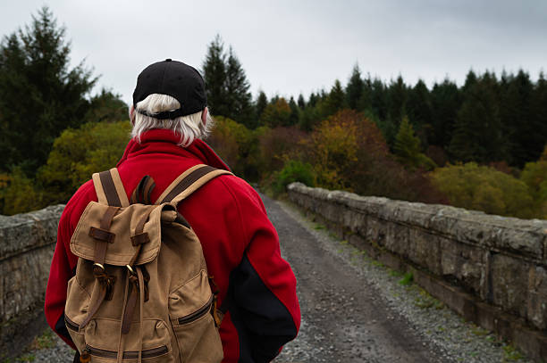 Rear view of a senior man standing on an old railway viaduct in a remote rural location in Scotland