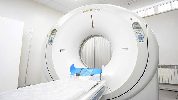 CT scanner machine in a bright medical room, featuring a patient bed and control panel, illustrating advanced imaging technology for x-ray diagnosis and tomography procedures