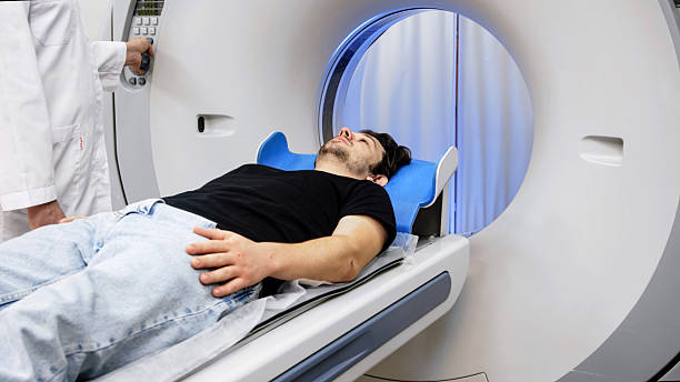 istock Patient lying on CT scanner table, preparing for tomography procedure, with medical staff nearby, showcasing advanced imaging technology in a clinical environment 2244162742