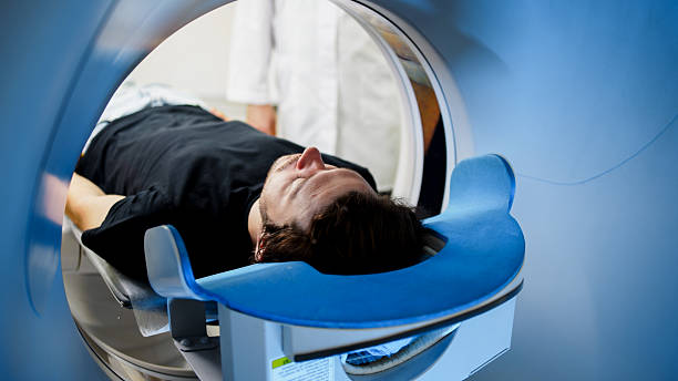 Patient undergoing CT scan in modern medical facility, lying on examination table, with advanced imaging equipment and healthcare professional present, illustrating diagnostic technology