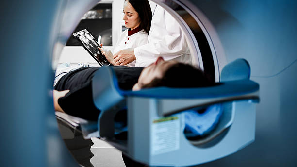 istock Medical professional analyzing CT scan results while patient lies on examination table inside CT scanner, showcasing advanced imaging technology and diagnostic procedures 2244162758