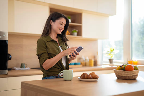 istock Woman using smartphone in kitchen enjoying morning breakfast 2244165085