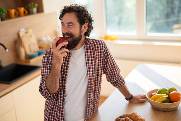 istock Man eating fresh apple in kitchen enjoying healthy breakfast 2244165154