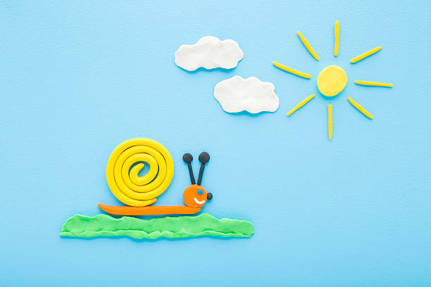 Created snail, sun and clouds from colorful modeling clay on light blue table background. Pastel color. Closeup. Little child handcraft. Top down view.