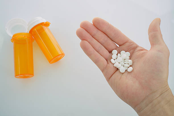 istock Man's Hand Holding White Pills with Medicine Bottles 2244166715