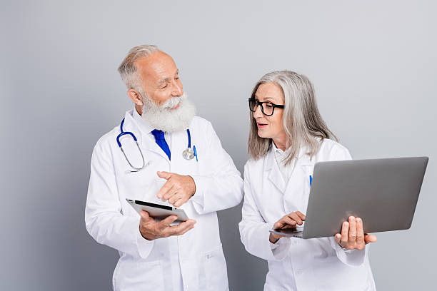 istock Two experienced doctors in white coats review tablets and laptop during a collaborative medical consultation in a clinical setting 2244166955