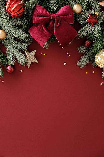 istock Christmas vertical background with pine branches, red velvet bow, baubles, glitter star and confetti on red background. Perfect for holiday greeting, banner or seasonal promotion. 2244167772