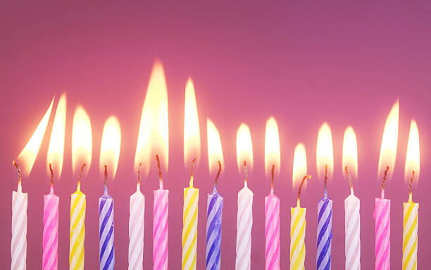 istock Colourful birthday cake candles burning on pink 2244174007