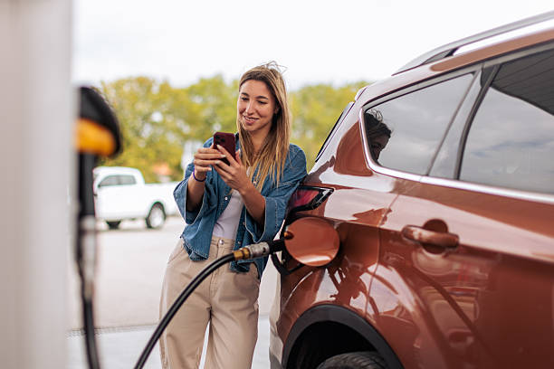 istock Woman Using Phone While Car Refuels at Gas Station 2244175964