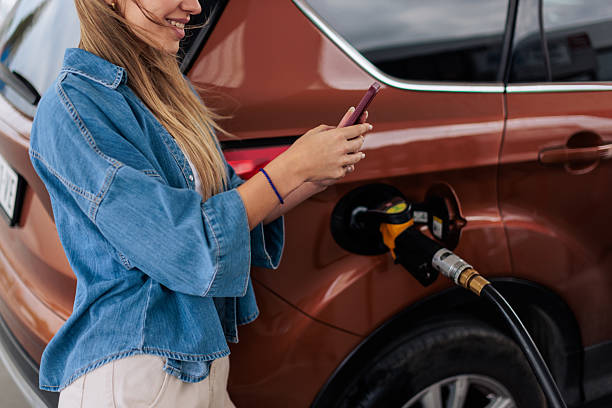 istock Woman Using Phone While Car Refuels at Gas Station 2244177466