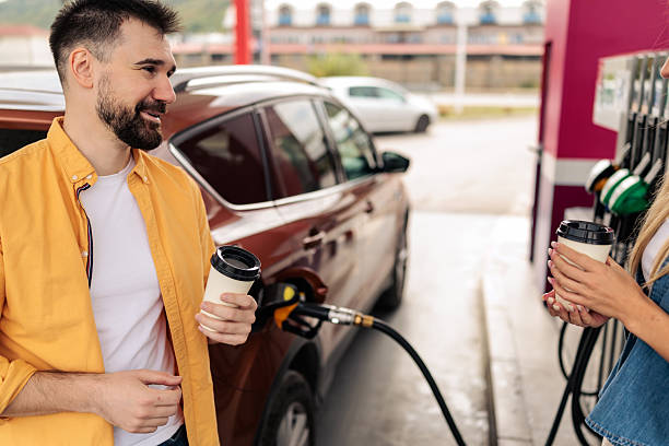 istock Couple Enjoying Coffee While Refueling Their Car 2244178644