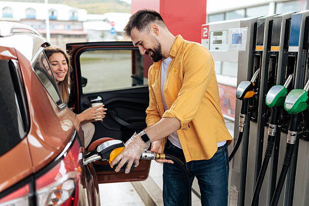 istock Smiling Couple Refueling Car at Gas Station 2244178818