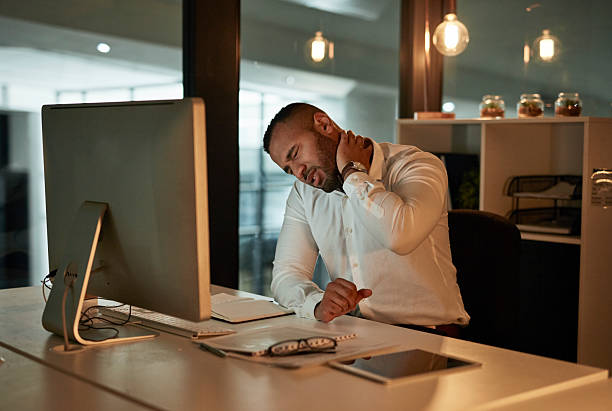 istock Stressed Professional At Desk Massaging Neck During Late Night Office Work In Open Plan Office 2244180038