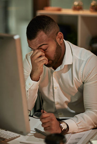 istock Fatigued Office Worker Rubbing Eyes At Desk With Computer And Notepad In Quiet Office 2244180055