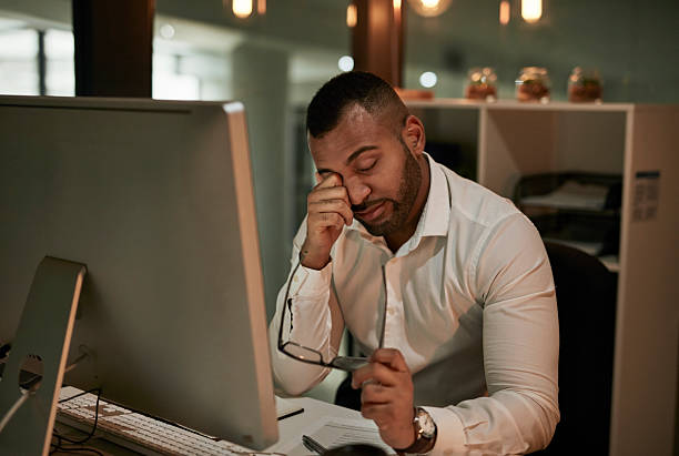 istock Tired Office Worker Rubbing Eye at Desk with Computer and Glasses, Late Night Stress 2244180057