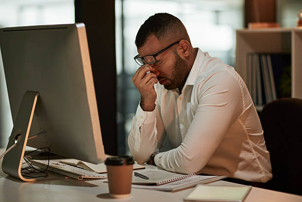 istock Stressed Office Worker Rubbing Eyes At Desk With Computer, Notebooks, Coffee Cup, in a Quiet Office 2244180066
