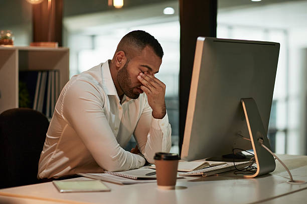 istock Stressed Office Worker Sits Beside Computer, Head In Hand, Focusing On Fatigue At Work 2244180077