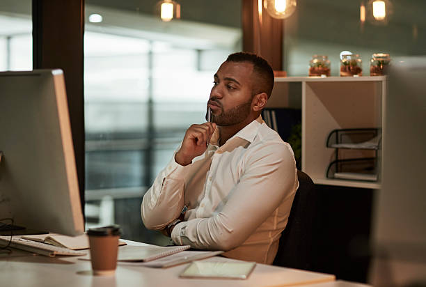 istock Professional Man Deep In Thought At Desk In Modern Office With Computer And Coffee Cup 2244180081