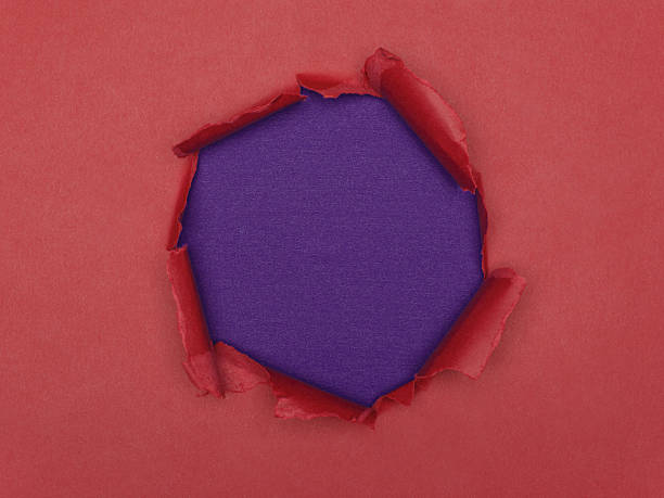 istock Torn hole in red paper revealing a textured purple background. 2244183006