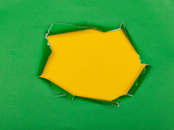 istock Torn hole in green paper revealing a textured yellow background. 2244183015