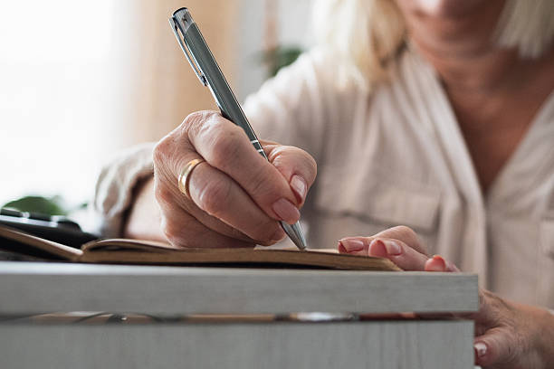 istock Senior woman writing notes in a personal notebook 2244189224