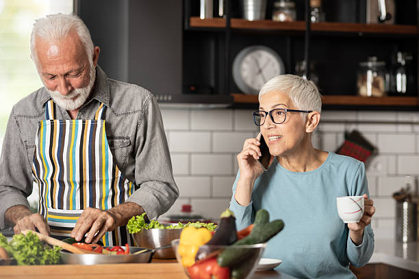 istock Smiling woman talking on phone while standing with man in kitchen 2244189932