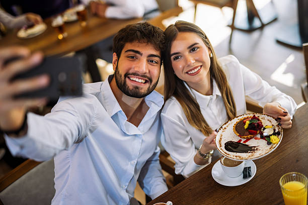 istock Couple taking selfie while eating cake in restaurant 2244191469