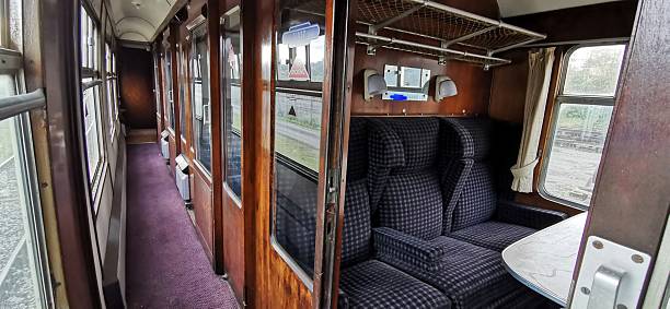 istock Derelict empty interior of old fashioned train carriage compartments. Deserted railway car hallway. Long narrow corridor with passenger cabin seats, tables, windows. Quiet rail journey nostalgia, travelling on declining mode of transportation. 2244193279