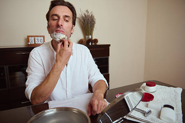 Man Shaving At Home With Razor And Cream In Quiet Bathroom Setting