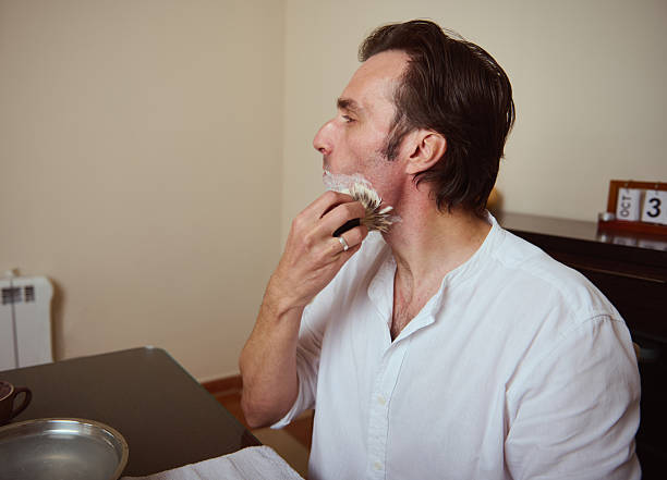 istock Man Shaving With Brush At Home In White Shirt During Morning Routine 2244194195