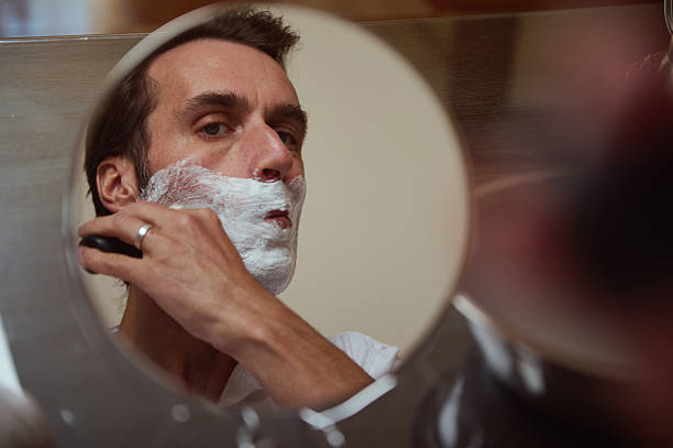 istock Man Shaving in Front of Mirror With Foam in Bathroom During Morning Routine 2244194266