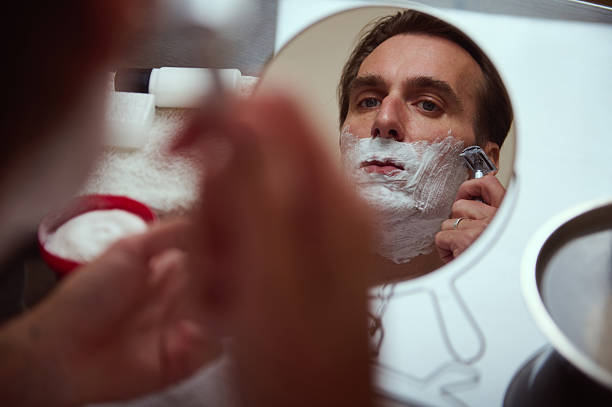 istock Man Shaving in Mirror: Bathroom Grooming Routine With Foam and Razor 2244194272