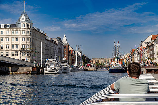 Copenhagen, Denmark-August 14, 2025: View from a tour boat cruising down Copenhagen canal, yachts and historic architecture line both sides, clear summer sky.