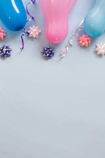 Birthday party background with balloons, streamer, and ribbons on a pastel blue surface.