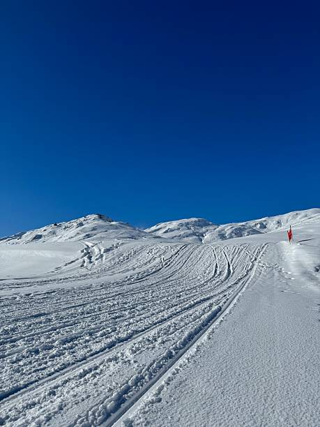 Empty Groomed Ski Slope with Fresh Snow Tracks on Sunny Day View