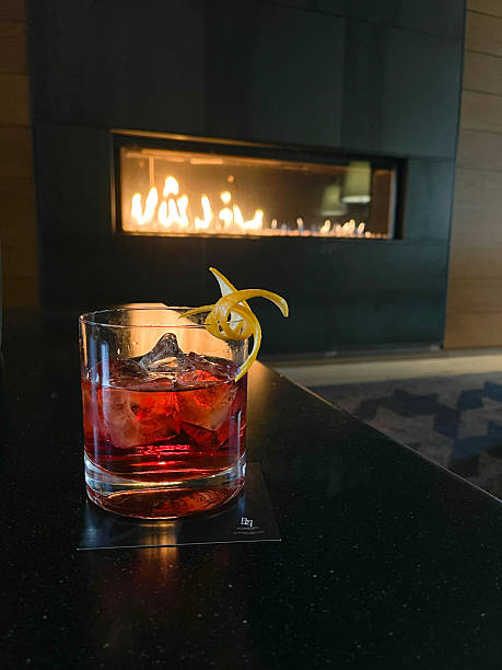 istock Red Cocktail with Lemon Twist on Rocks by Modern Fireplace at Night 2244199274